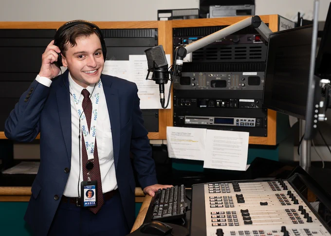 a photo of a person in a radio recording studio holding a pair of headphones on his head