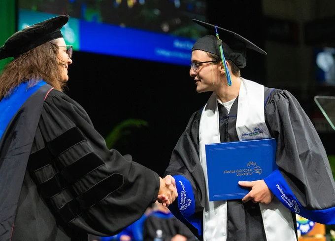 a photo of a student shaking hands at graduation