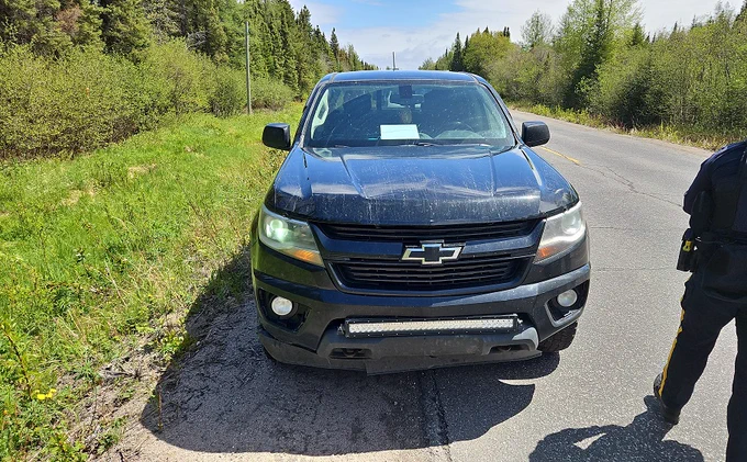 Une camionnette noire en bordure de route.

