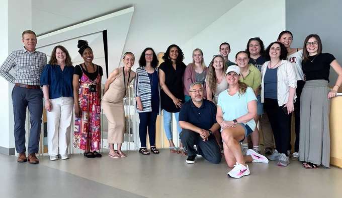 A group of 16 people from different backgrounds pose for a group picture. 
