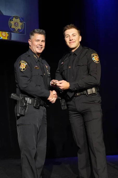 Deputy shaking hands with Sheriff Weekly, receiving their badge.