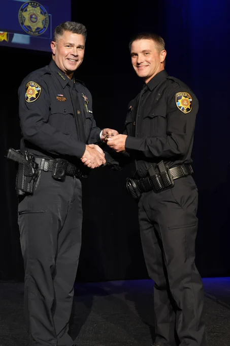 Deputy shaking hands with Sheriff Weekly, receiving their badge.