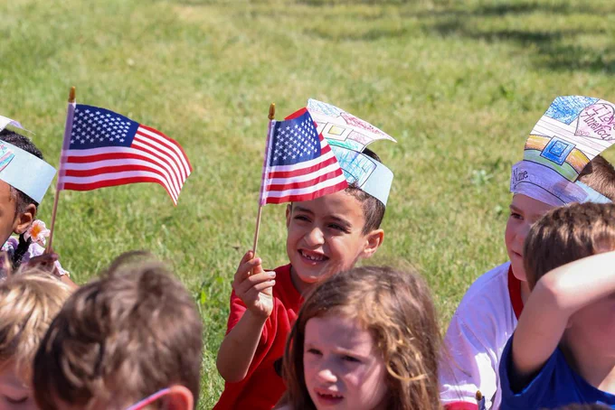 student holds up flag and smiles 