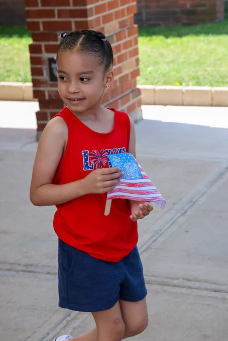 student walks with paper drawn flag and smiles