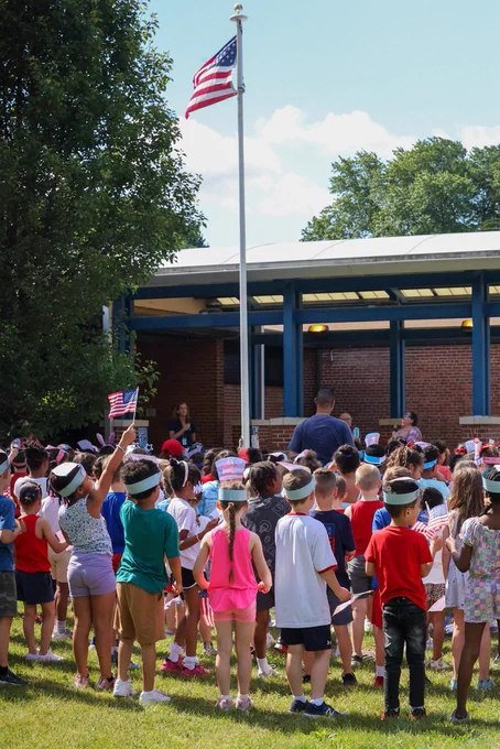a group of students stand outside and recite the pledge