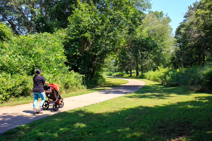 A woman walking with a stroller on the North Oconee River Greenway in Athens, GA.