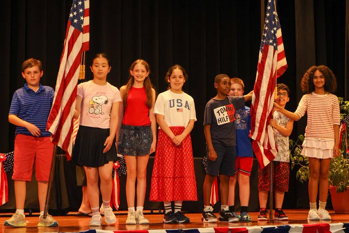 students stand on stage as new and existing flag bearers at the school 