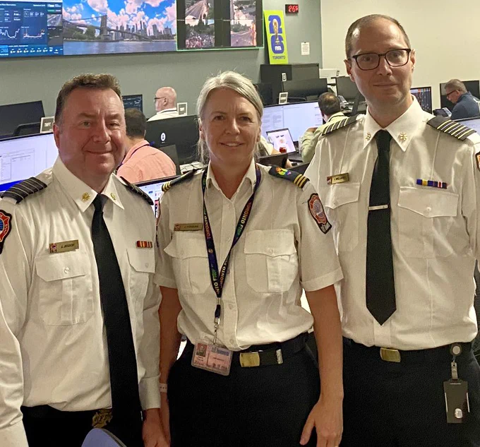 The Toronto Fire Chief standing alongside two Toronto Fire Services senior staff. There are computer screens and screens in the background.