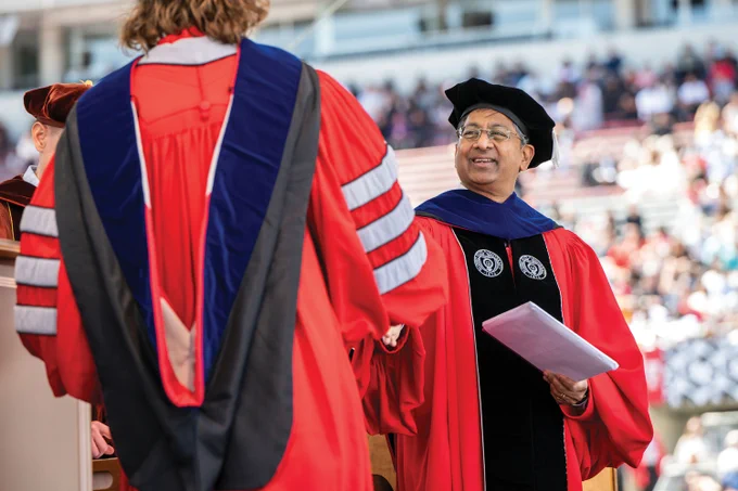 Ravi Bellamkonda in full regalia onstage at commencement shaking the hand of a PhD graduate