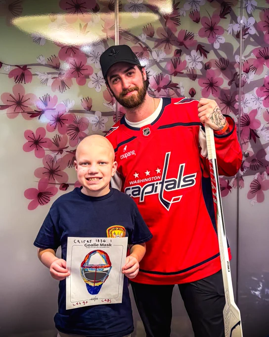 Logan Thompson smiles for a photo with William Martel, a young Caps fan battling a rare brain tumor. William is holding up his goalie mask design from today's design session with LT.
