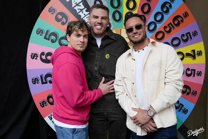 A group photo of Kiké Hernández, Freddie Freeman and Miguel Rojas posing in front of the Wheel of Fortune wheel.