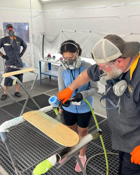 A camper practices spray painting with guidance from instructors.