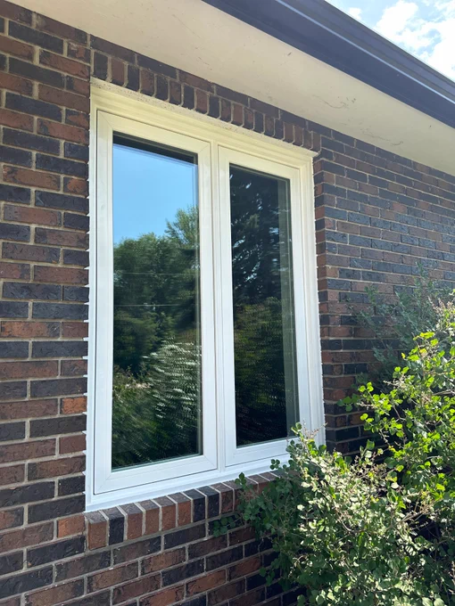 White custom window installation in brick Manitoba home exterior with energy-efficient locally manufactured window system.