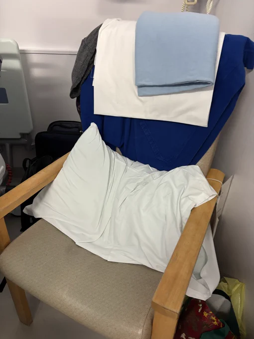 Hard upright chair with pillow and sheets on adult ward . the sleeping arrangement for a carer