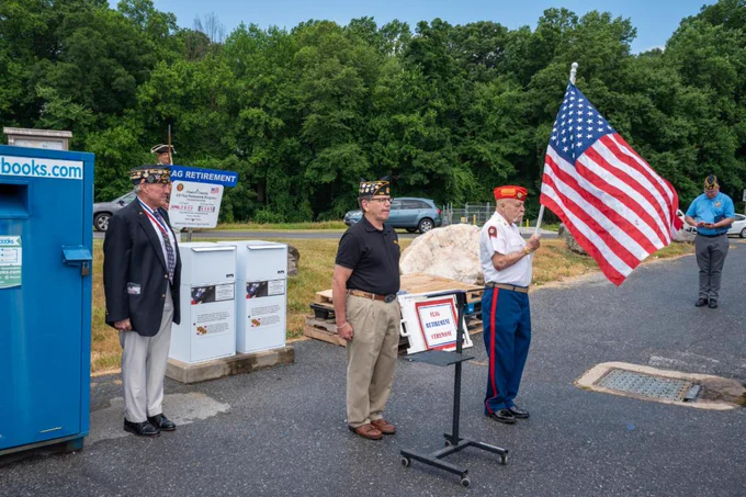 Veteran in uniform holding an American flag during a flag retirement ceremony at the Alpha Ridge Landfill.