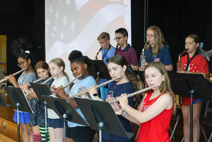 students play instruments in band with flag in the background