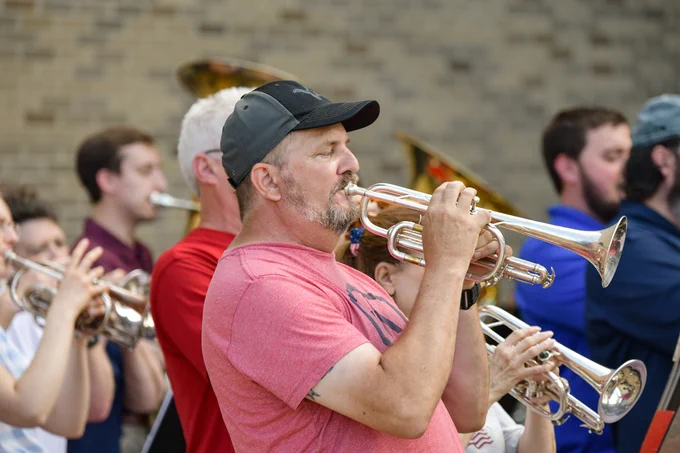 Group of musicians playing trumpets outdoors during the Capital City Brass Band concert. 