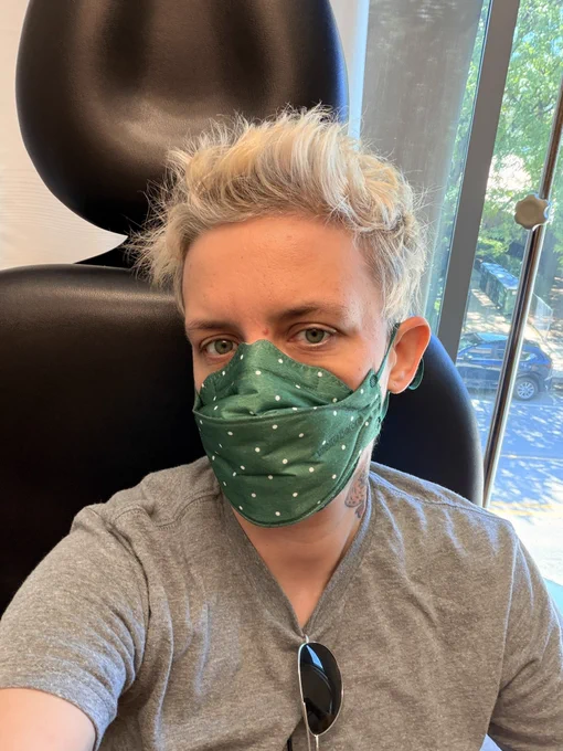 Selfie wearing green polka dotted n95 mask sitting in a doctor’s office