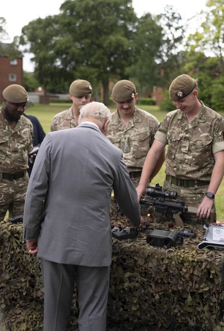 The King inspects drone equipment displayed on camouflage netting covered table with the Grenadier Guards outside in their barracks in Aldershot