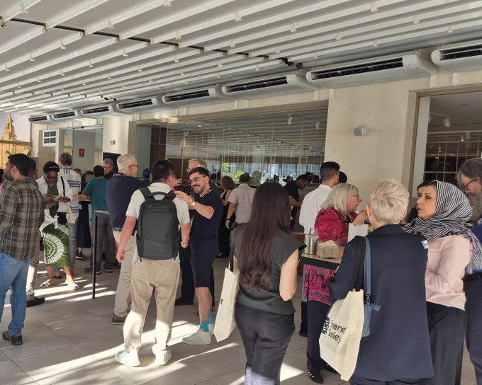 A large group of people stand outside and socialize