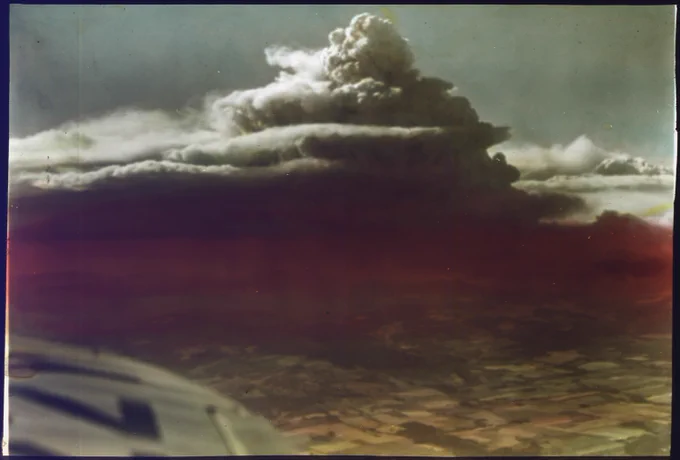  Photo of one of the Tillamook Burn fires in August 1933 by Unknown author from an airplane featuring a dark black cloud made of smoke over a fire on the ground below.