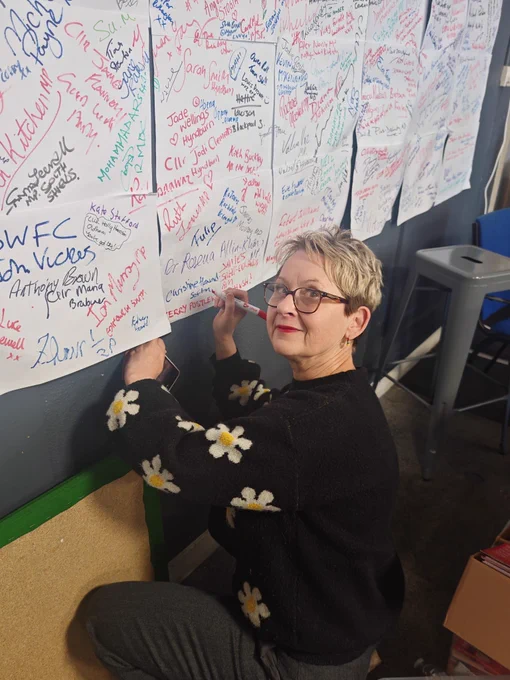 Kerry writing her name on the wall of activists’ names.