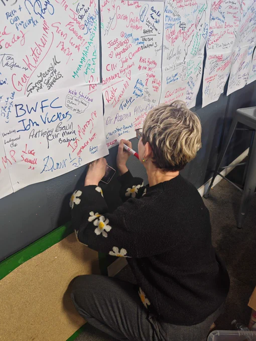 Kerry writing her name on the wall of activists’ names.