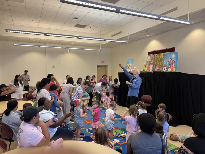Group of parents and children enjoy puppet show.