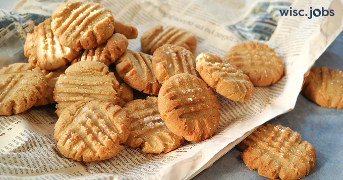 Image: peanut butter cookies with crisscross fork marks scattered on paper; Wisc.Jobs