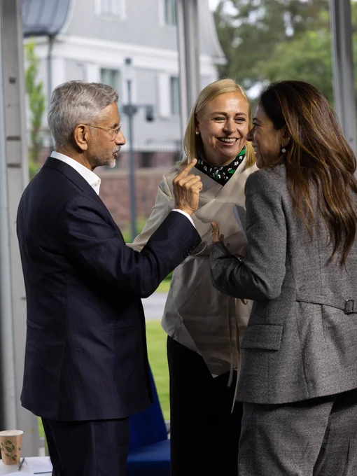 India’s Foreign Minister Subrahmanyam Jaishankar, Finnish Foreign Minister Elina Valtonen, and UAE Minister of State Lana Nusseibeh standing together in a discussion, smiling brightly.