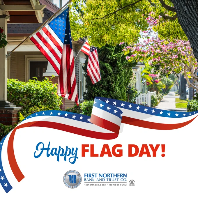 American flags displayed on porches with flowers blooming from trees.
