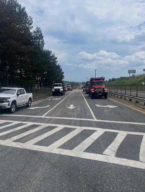 Photo of some large trucks blocking off two lanes with one lane open. 