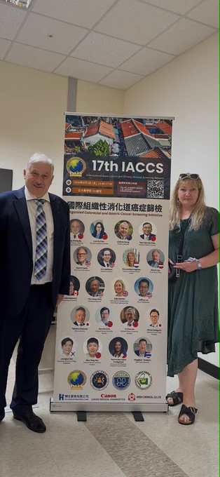Professor Marcis Leja and Project Coordinator Iveta Enina from the University of Latvia stand beside a conference banner at the 17th International Asian Cancer and Chronic Disease Screening (IACCS) Conference in Taiwan. The banner features international experts in cancer screening and highlights organised colorectal and gastric cancer screening initiatives. The photo was taken during the EUCanScreen representatives’ visit to Taiwan to exchange knowledge on innovative cancer screening approaches and international collaboration.