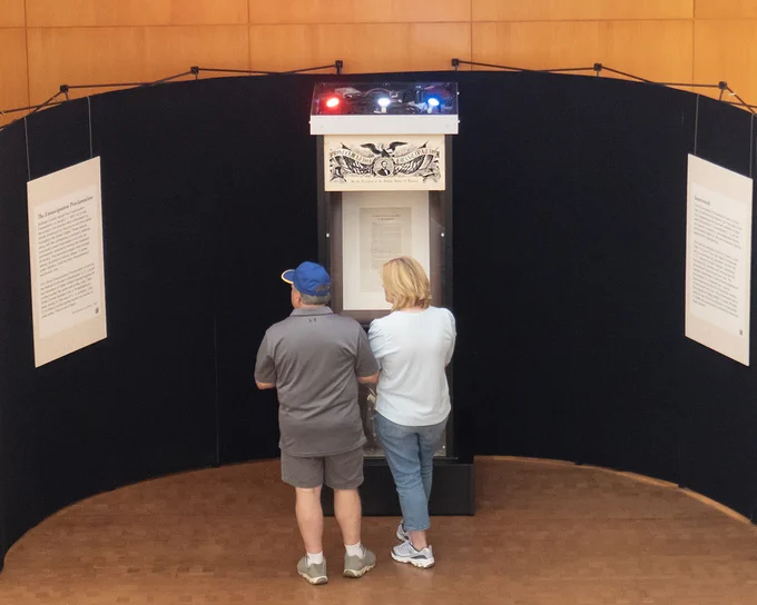 Two people looking at a museum display case containing a signed copy of the Emancipation Proclamation.