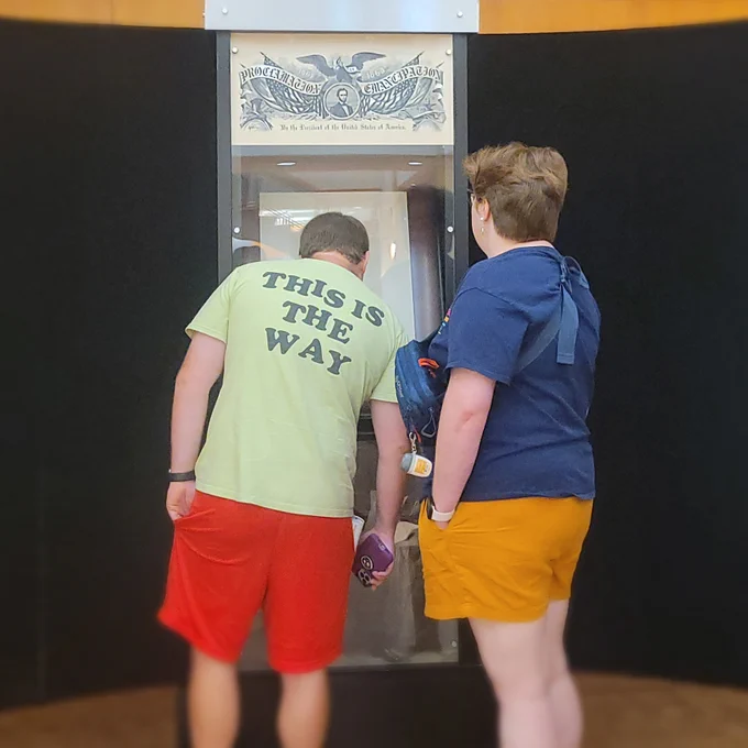 Two people looking at a museum display case containing a signed copy of the Emancipation Proclamation.