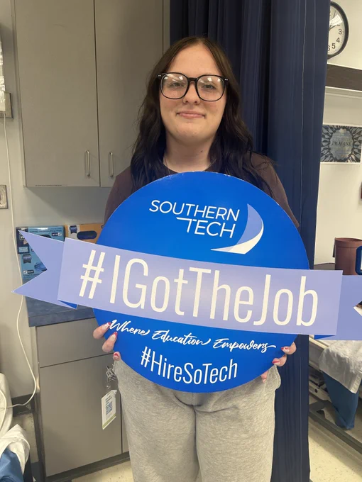 student holding an I got the job sign.