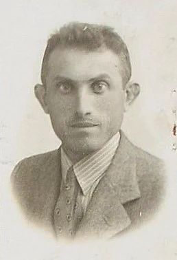 Black and white vintage portrait of a man wearing a suit and striped tie, looking directly at the camera.
