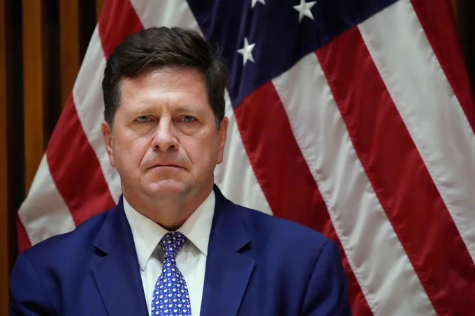 Jay Clayton in front of American flag