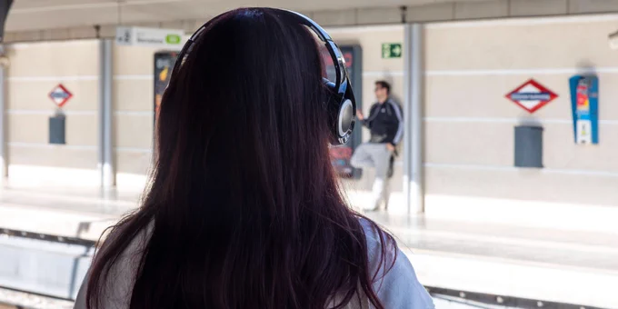 Noia amb auriculars a l'estació d'Universitat Autònoma. 