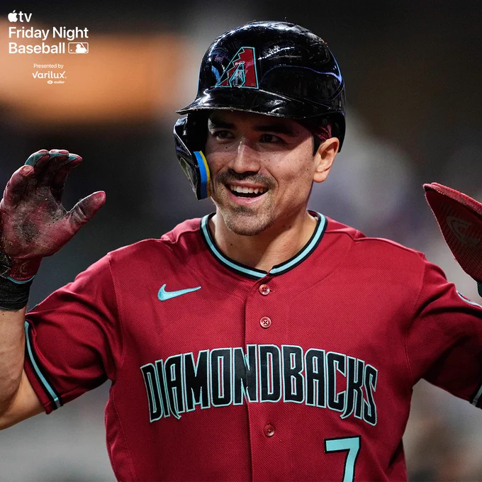 Corbin Carroll smiles walking to the dugout. He is wearing a red D-backs jersey.