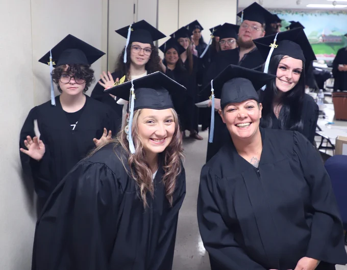Group of graduates in caps and gowns posing together before a ceremony.