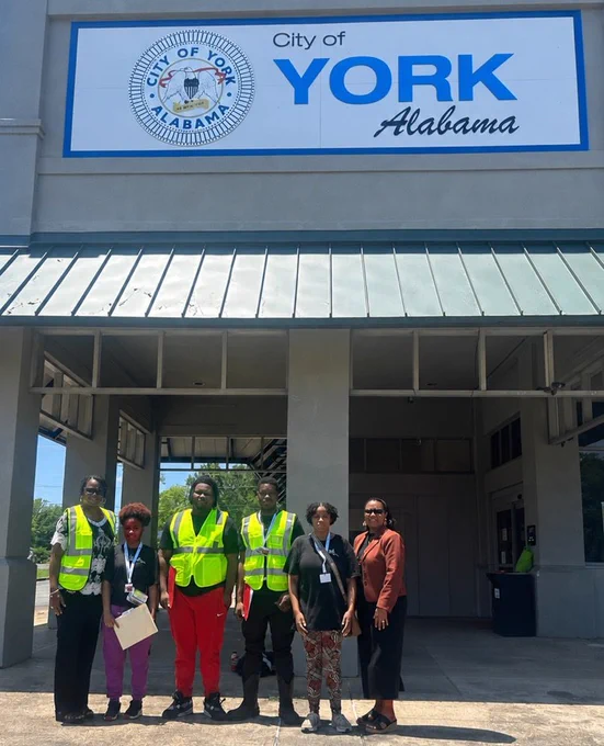 group of six standing in front of the city of York building 