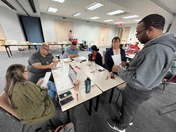 Department of Neighborhoods staff participate in a hands-on emergency preparedness training session. Participants are seated around tables reviewing shelter activation materials, discussing procedures, and collaborating on response scenarios. The training, conducted in a classroom setting, focuses on preparing team members to support emergency shelter operations and assist residents during disasters and severe weather events. The interactive session helps strengthen the Department's role in the Houston Emergency Response Team (HERT) program and enhances readiness to serve the community when emergencies arise.