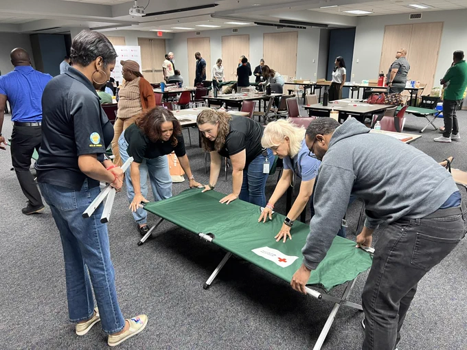 Participants engage in a hands-on emergency shelter operations exercise during an American Red Cross training session. Working together in small groups, attendees assemble a shelter cot while learning the procedures and equipment used to support residents during disasters, severe weather events, and other emergencies. The interactive training provides practical experience in shelter setup and operations, helping strengthen the Department of Neighborhoods' role in the Houston Emergency Response Team (HERT) program and ensuring staff are prepared to assist Houstonians when emergency sheltering is needed.