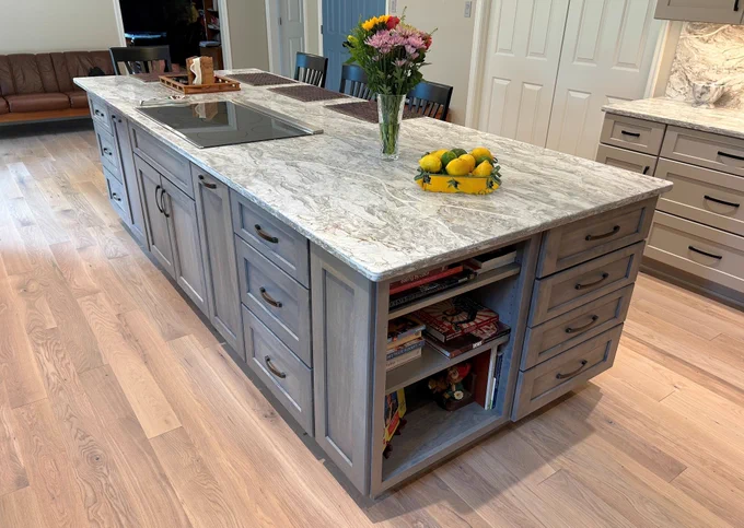 This Frederick-area kitchen remodel by Talon Construction Inc. is a standout example of how thoughtful design and craftsmanship can completely transform the heart of a home. Blending modern functionality with timeless finishes, the space is both visually striking and highly livable tailored to how homeowners cook, gather, and entertain.
At the center of the design is a large, statement island topped with marble-inspired quartz. Its expansive surface serves as a multifunctional hub for meal prep, casual dining, and socializing. The waterfall-like veining carries seamlessly into the full-height backsplash, creating a cohesive and elevated aesthetic that feels custom and refined. 
The cabinetry palette strikes a perfect balance between contrast and warmth. Crisp white shaker-style upper cabinets keep the perimeter light and open, while soft gray base cabinetry and a matching island ground the space with subtle depth. 