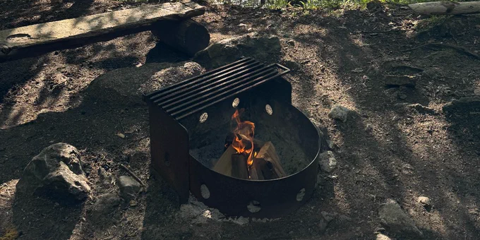 a burning campfire in a steel campfire pit located at one of the campsites at Frontenac.