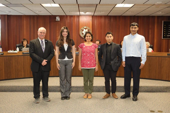 Four student trustees with the board president at the board meeting.