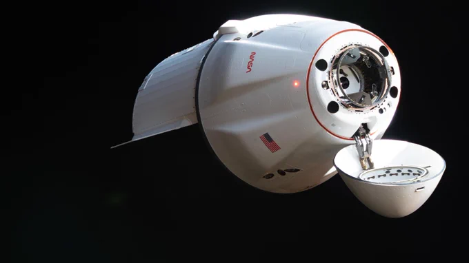 A SpaceX Dragon spacecraft, seen close-up in space. Its conical nose cone is open, revealing the docking port beneath. Credit: NASA