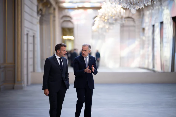 Prime Minister Mark Carney and the President of France, Emmanuel Macron, are conversing while walking through le Palais de l’Élysée.