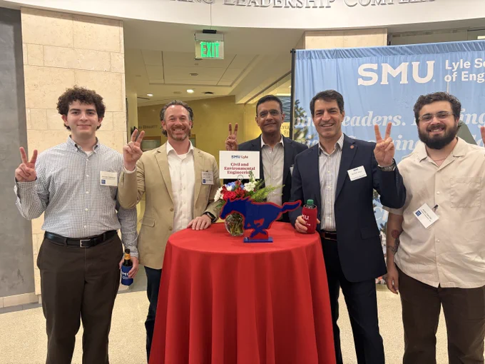 Dean Jalili, CEE faculty, and incoming students are standing around a table at an SMU Lyle School of Engineering admitted students event. Everyone is doing the "Pony Up" hand sign.
